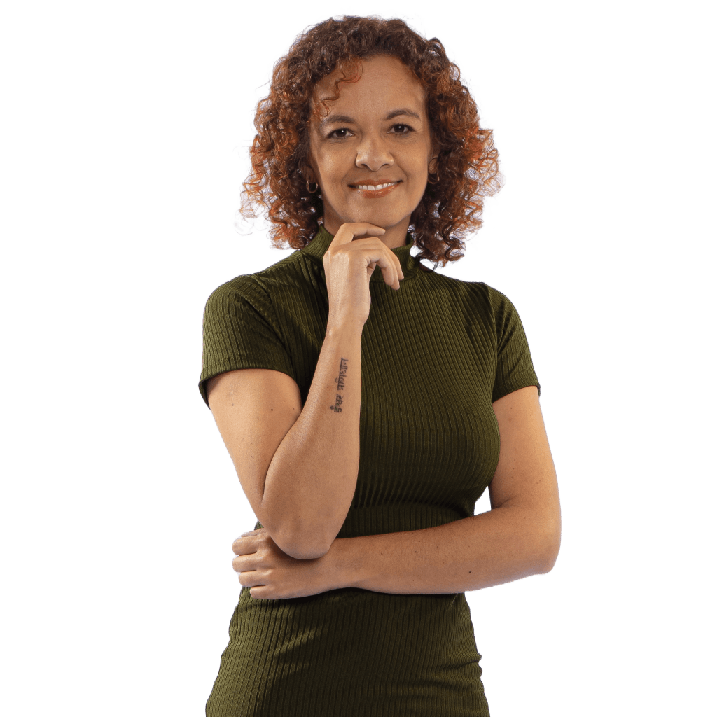 Mulher negra com blusa verde posando para foto com mão no queixo.