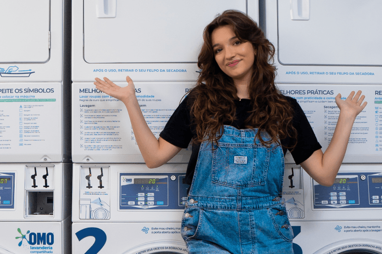 Mulher encostada nas máquinas da OMO